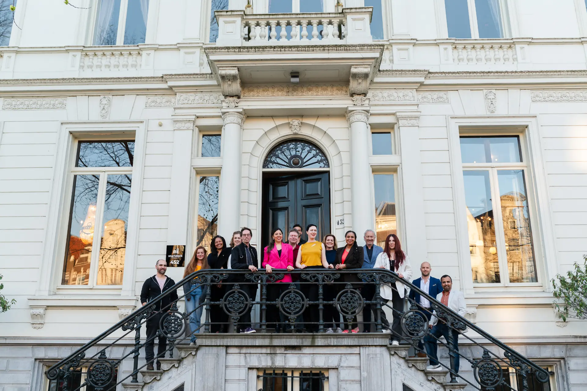 Een groep mensen op de trap buiten een coworking-ruimte aan de Herengracht in Amsterdam